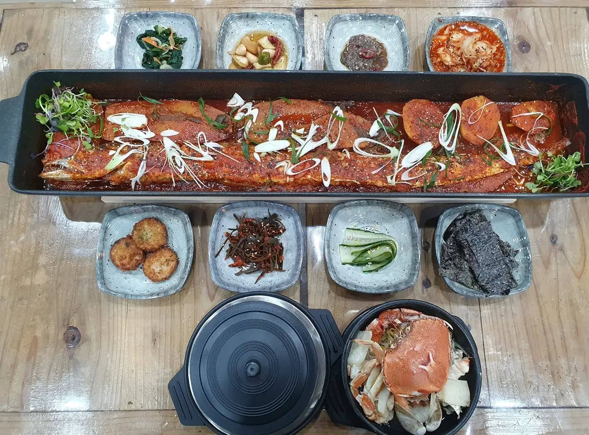 Historical whole-hairtail braise and side dishes at Jeju Aewol Seafood Feast.