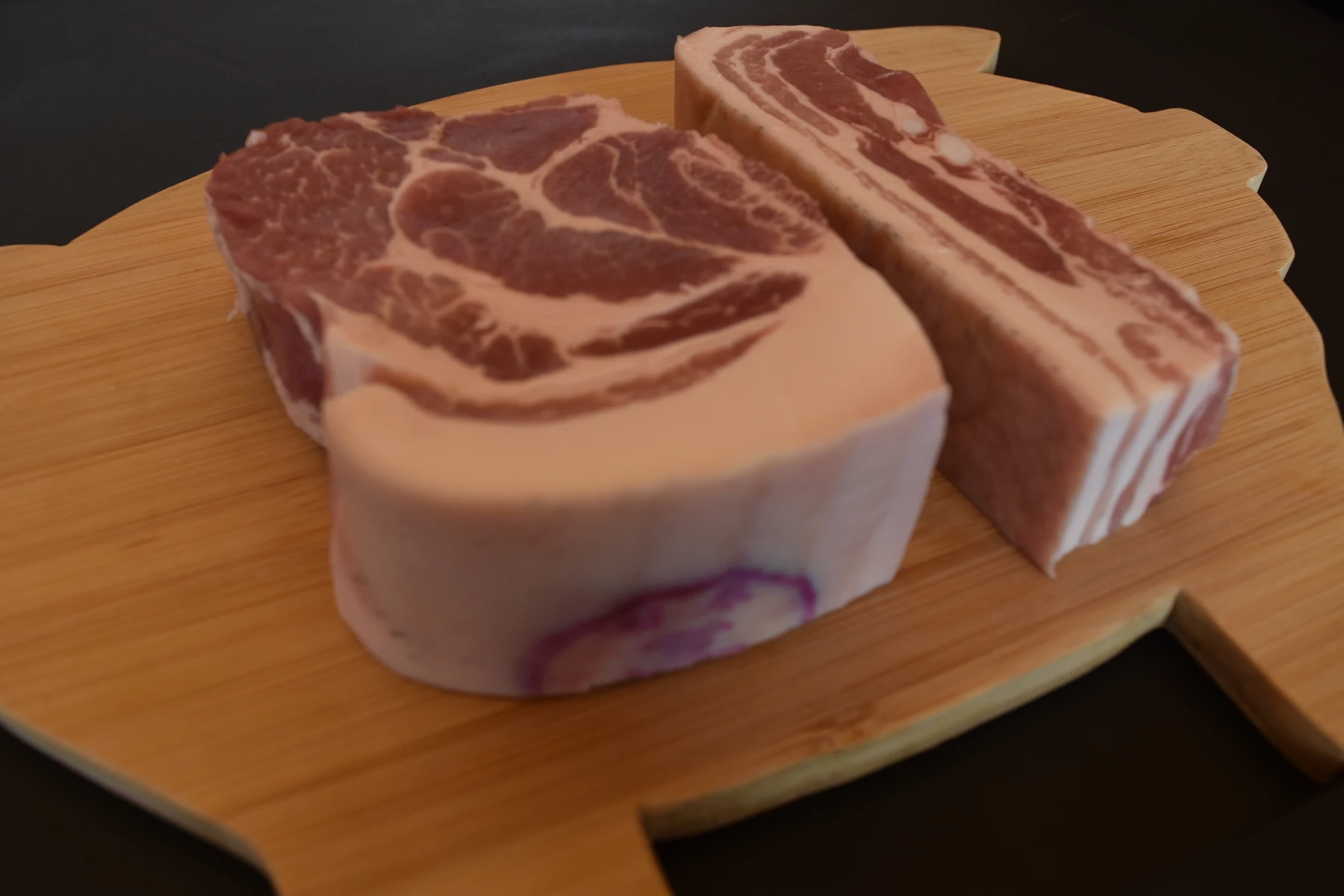 Thick raw pork cuts on a wooden board from Mokpogoeul's company gallery.