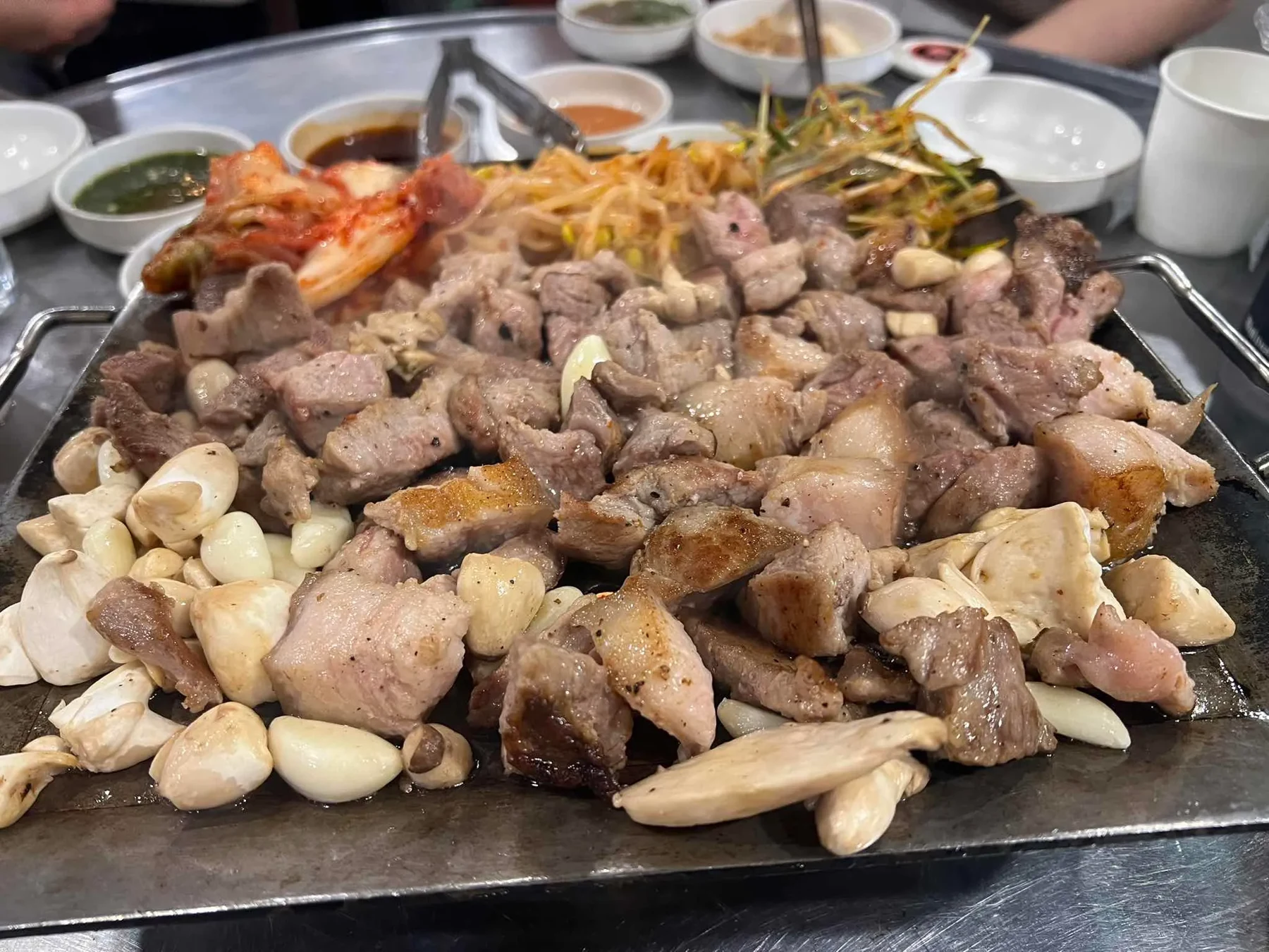 Pork grilling with garlic, kimchi and sprouts at the Gwangalli branch, from a June 2026 visitor review.